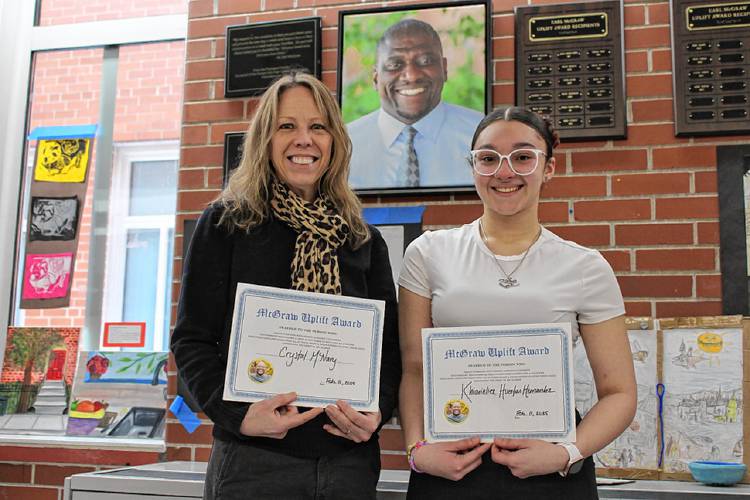 From left, special education teacher Crystal McNary and Turners Falls High School senior Khiarieliex Huertas Hernandez stand together in front of the portrait of beloved late Assistant Principal Earl McGraw in the lobby of the school after receiving the McGraw Uplift Awards named in his honor on Tuesday, Feb. 11.