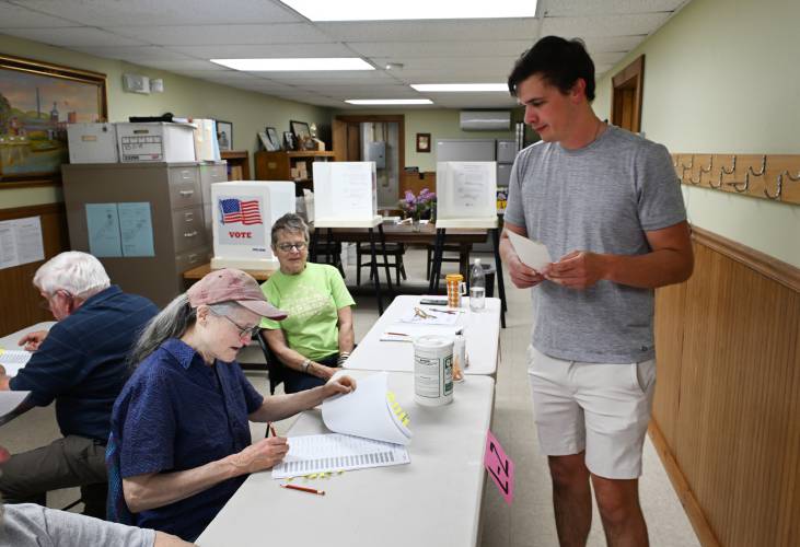 Poll workers Susanne Hale and Jade Mortimer check Robert Slowinski out after voting at the Town Offices in Colrain on Tuesday.