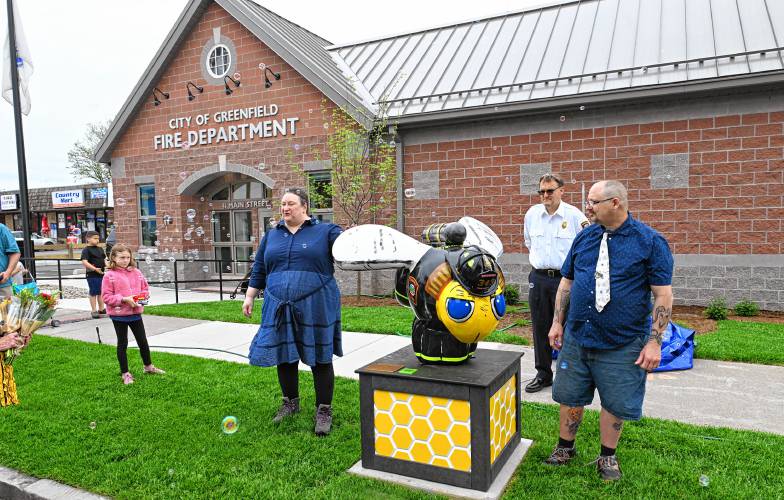 Sculptor Rachel Katz and painter Andrew Easton, with Fire Chief Robert Strahan in back,  reveal the newest bee in town in front of the new Greenfield Fire Station called Fearless complete in turn out gear. 