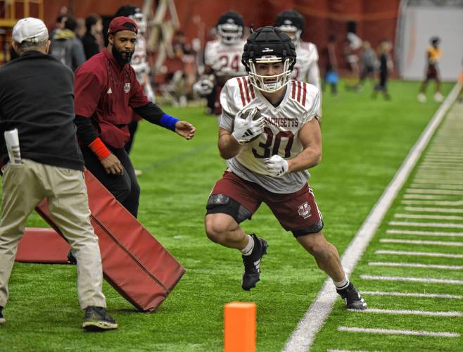 UMass running back Cookie Desiderio (30) goes through a drill while running backs coach Jeremy Larkin looks on during the Minutemen’s first football practice of the spring season on Monday morning in Amherst.