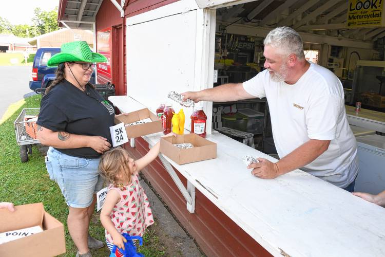 Bernardston resident Brian Hervieux hands out hot dogs at the first stop on the rodeo-themed Big Brothers Big Sisters Point 5K fundraiser on Thursday at the Franklin County Fairgrounds.