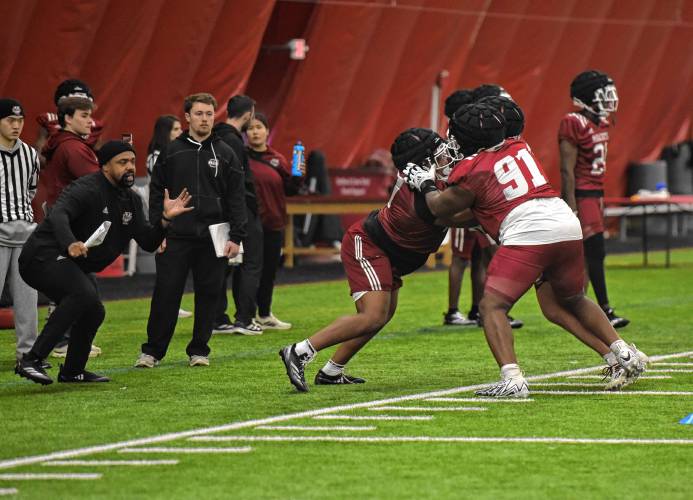 UMass defensive lineman Shymell Davis (91) participates in a drill while defensive line coach Nyeem Wartman-White, left, looks on during the Minutemen’s first football practice of the spring season on Monday morning in Amherst.