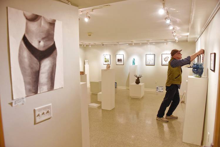 Artspace Community Arts Center Board President Stephen Hussey hangs artwork for the 50th annual Teen Art Show at the Mill Street gallery in Greenfield.