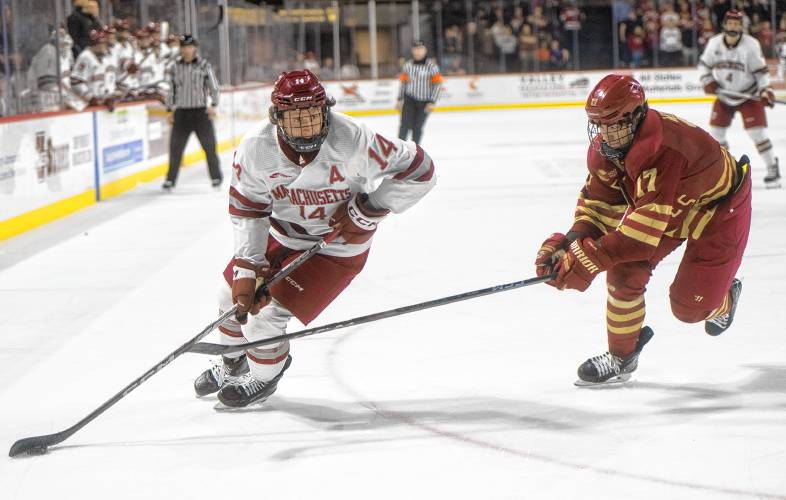 UMass right wing Ryan Lautenbach (14) keeps the puck from Boston College defenseman Aram Minnetian (17) during the college hockey game at the Mullins Center, Saturday, Feb. 15, 2025, in Amherst.
