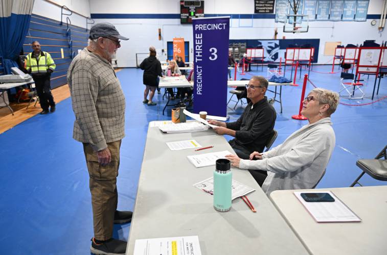 Harold “Sandy” Jensen is checked in to vote at Franklin County Technical School in Montague by Frank Lapachinski and his wife Terry Lapachinski.