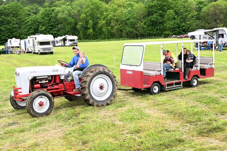 Rowe resident Austin Willis holds his 3-year-old daughter Harley on his tractor as they pull people around Pratt Field during the 49th annual Gas Engine Show, Flea Market & Craft Fair at Pratt Field in Bernardston on Friday.