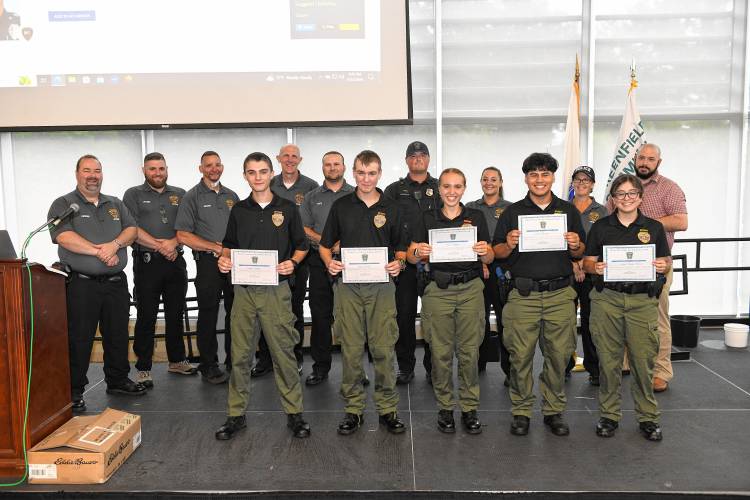 Tommy Nutting, Wyatt Dejnak, Nina Dejnak, Carlos Ramirez and Lillian Ramos-Oliva stand with certificates from the Franklin County Police Cadet Program with their advisers behind them at Greenfield Community College on Wednesday.