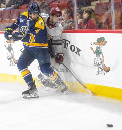 Merrimack defeseman Seamus Powell (4) and UMass forward Joey Musa, right, compete for the puck during Saturday’s hockey game at the Mullins Center in Amherst.
