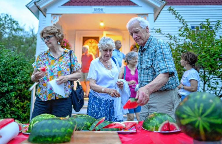Attendees help themselves to sliced watermelon at intermission during a Watermelon Wednesdays concert at the West Whately Chapel.