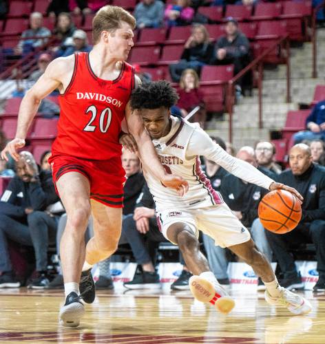 UMass guard Jaylen Curry, right, dribbles into Davidson guard Zach Laput (20) during the college basketball game at the Mullins Center, Wednesday, Feb. 12, 2025, in Amherst.