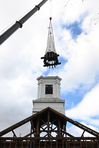 The steeple of the former Zion Korean Church on Main Street in Greenfield is hoisted off the base on Wednesday as the church next to Franklin County’s YMCA is headed back to Barre, where it was first located.