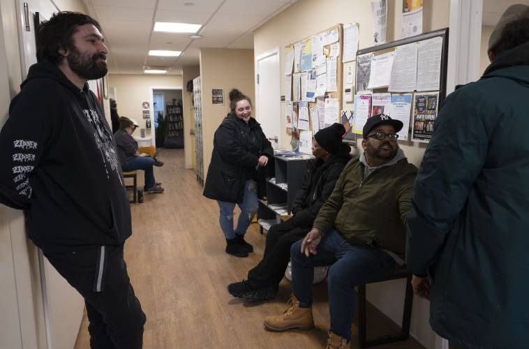 Matty Hollander, community coordinator in Hampden County, Earle Miller, director of community supports, and George Alexander Jr. talk in the hallway at the Wildflower Alliance Bowen Center in Springfield. “The job is hard but the people are good,” said Miller about his work day.