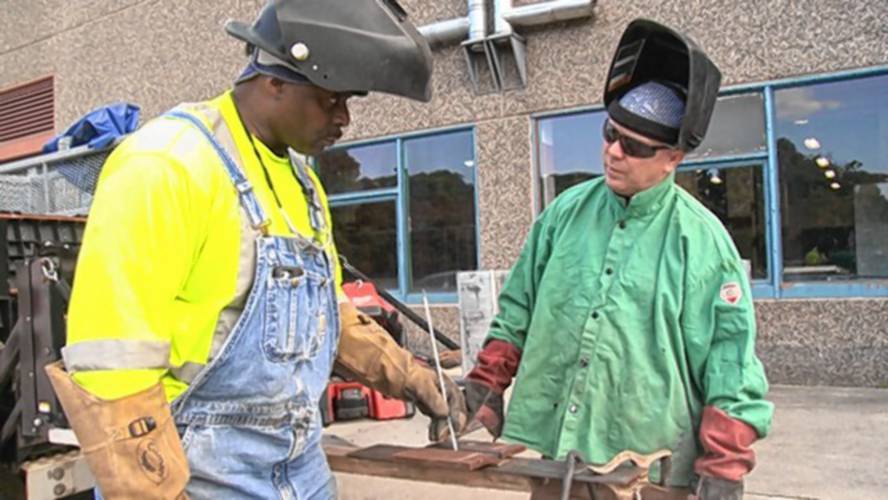 In this still image from the documentary film “Holding Up The Sky,” master welder Ed Jordan, left, teaches apprentice Jimmy Costello. Jordan mentored Costello when they were both in prison in Walpole. Both are featured in “Holding Up The Sky,” which will be shown as part of a program at Orange Innovation Center on June 30.