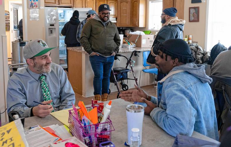 Norman DeGray, front left and Uno Brown, front right relax and talk in the kitchen and lounge area of the Wildflower Alliance Bowen Center in Springfield. Earle Miller, middle, is director of community supports.