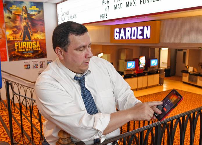 Isaac Mass of Greenfield’s Garden Cinemas displays the TheaterEars app on his phone that allows viewers to hear movies in Spanish. 
