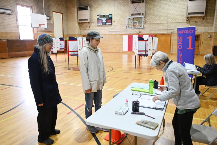Shelburne residents Sarah Pirtle and Emily Stone are checked in to vote at Cowell Gymnasium by election worker Rita Jaros on Tuesday.