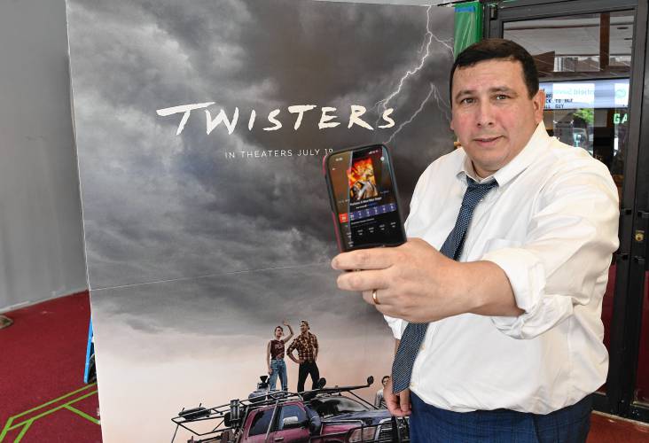 Isaac Mass of Greenfield’s Garden Cinemas displays the TheaterEars app on his phone that allows viewers to hear movies in Spanish. 