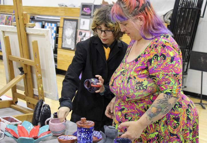 Turners Falls High School sophomore Ash Shipley-Aja shows his mother his ceramic artwork before taking the stage to perform in the choir during the 2025 Arts Night at Turners Falls High School and Great Falls Middle School on May 16.