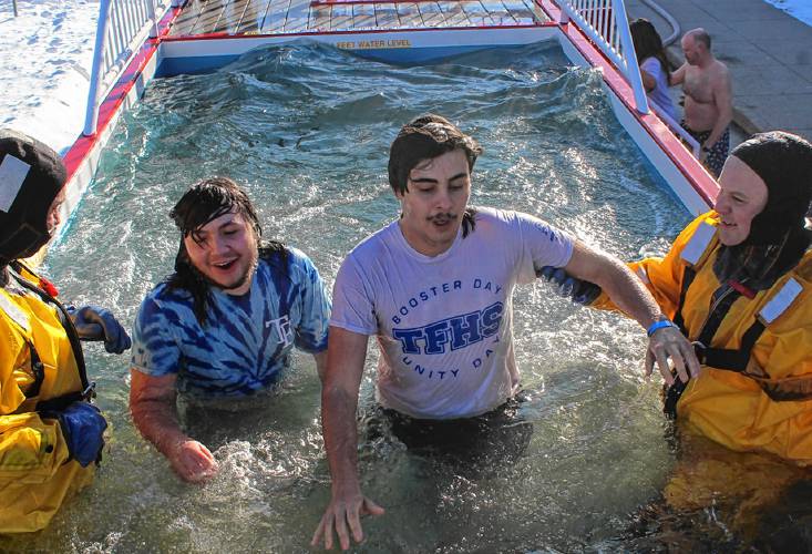 Capt. John Whitney, at left, of the Greenfield Fire Department and firefighter Michael Cachat help Vaughn LaValley and Estes Lemerise-Reinking from Turners Falls High School exit the polar plunge tank at Greenfield High School Thursday afternoon.