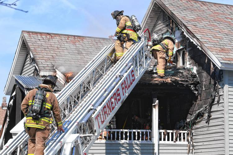 Firefighters extinguish a fire that scorched the rear of a two-family residence at 20 Elm St. in Greenfield on Wednesday.