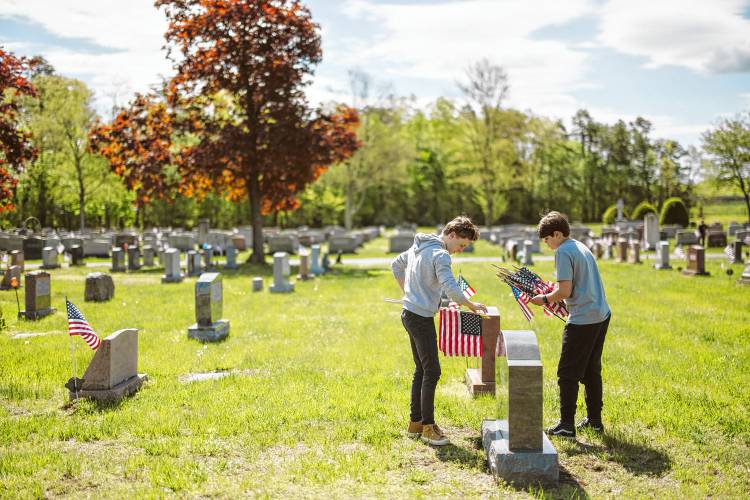 Greenfield High School Student Council members Julian Cavanaugh and Shane Toomey help with placing flags for veterans at Calvary Cemetery on May 11.