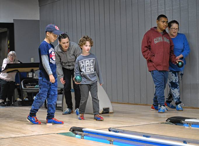 Joanne Larson helps James Sinclair, 9, and Ethan, 7, bowl as Dezmin Peoples, 12, is helped by his grandmother Karen Gardner at right at the French King Bowling Center in Erving.