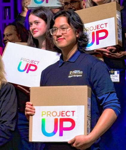 Samuel Pascual, a digital navigator with the Alliance for Digital Equity, and Hannah Cox behind him with their new laptops given as part of Comcast’s grant program Project Up. Digital navigators are employed with local agencies that team up to form a broad regional network that makes up the alliance.