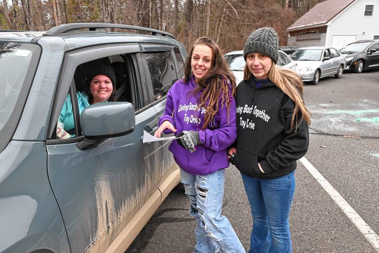Shelburne Falls resident Kelly Fortin picks up Christmas presents from Giving Back Together Toy Drive organizer Heather Taylor and Julie Comeau at Faith Church on Silver Street in Greenfield on Friday.