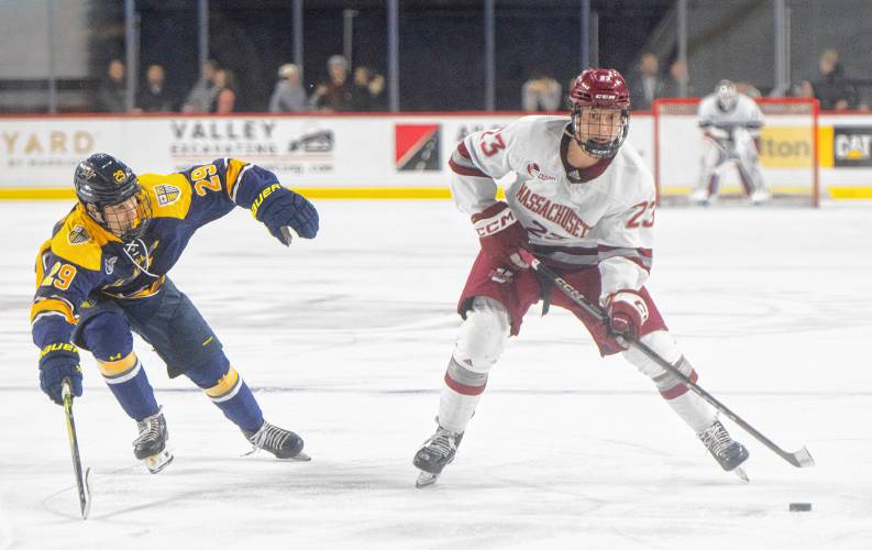 UMass defenseman Francesco Dell’elce (23) keeps the puck from Merrimack forward Caelan Fitzpatrick (29) during Saturday’s hockey game at the Mullins Center in Amherst.