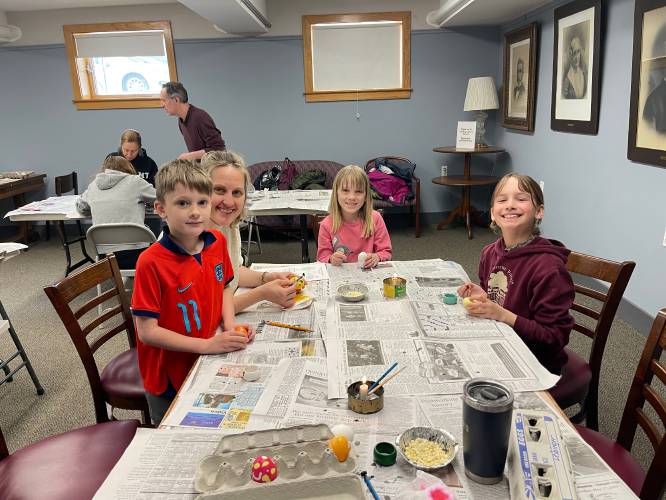 Tatiana Soper, second from left, and her children, 6-year-old Baer and 8-year-old Sage, decorate eggs with Ella Grace Leibinger, at right, at Belding Memorial Library in Ashfield.