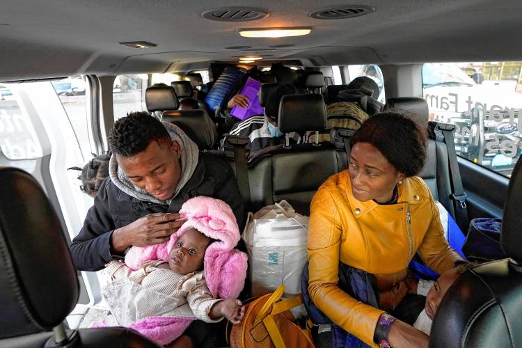 Petterly Jean-Baptiste holds a child as he and his wife, Leonne Ysnardin, both immigrants from Haiti, load into a van in Boston to await transportation to a shelter in Quincy in November. Petterly Jean-Baptiste holds a child as he and his wife, Leonne Ysnardin, both immigrants from Haiti, load into a van in Boston to await transportation to a shelter in Quincy in November.