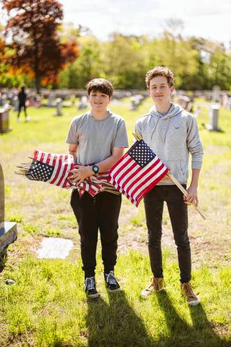 Greenfield High School Student Council members Julian Cavanaugh and Shane Toomey put out flags for veterans at Calvary Cemetery on Saturday, May 11.