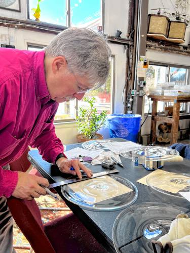 Shelburne glass artist Josh Simpson measures glass for a window before cutting it into a rectangle while contributing to the Buckland Historical Society’s Wilder Homestead restoration project.