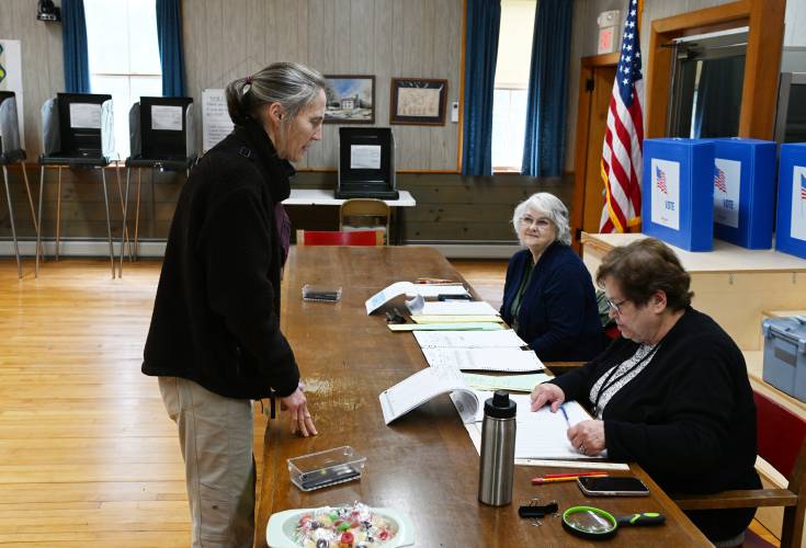 Lissa Greenough is checked in to vote by Gill election workers Ellen Hastings and Carol Lafleur at Gill Town Hall on Monday.