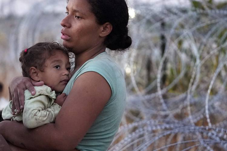 A woman carries her child after she crossed the Rio Grande from Mexico on Sept. 23 in Eagle Pass, Texas. A woman carries her child after she crossed the Rio Grande from Mexico on Sept. 23 in Eagle Pass, Texas.