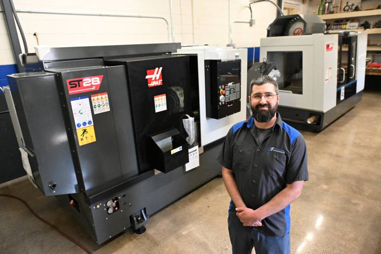 Eric Amato of Radial Dynamics in front of a computer numerical control lathe and mill that will be used in manufacturing hydraulic steering components at his Greenfield business.