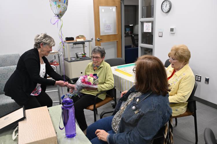Greenfield Mayor Ginny Desorgher presents Ferdinanda Uchman with flowers for her 100th birthday. Her friends and fellow Mahjong players at the Greenfield Senior Center organized a birthday party for her on Friday. She turned 100 on May 8.