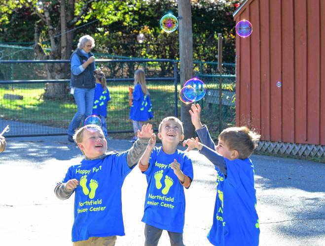 As part of the Happy Little Feet walking program, Northfield Elementary School kindergartners blow and catch bubbles on the school playground on Tuesday.