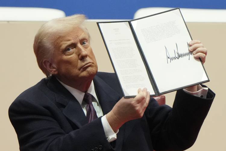 President Donald Trump holds up an executive order after signing it at an indoor Presidential Inauguration parade event in Washington, Jan. 20, 2025.