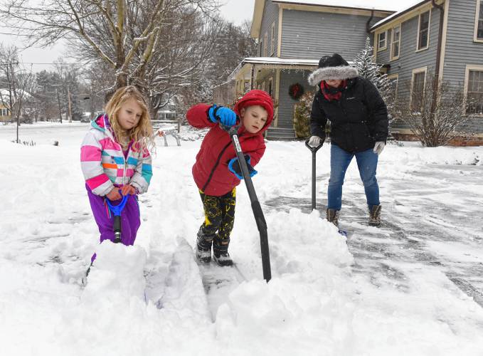 Emma Lindner, 4, and her brother, David Lindner, 7, help their mother, Mary Lindner, clear snow from the driveway in South Deerfield on Tuesday.