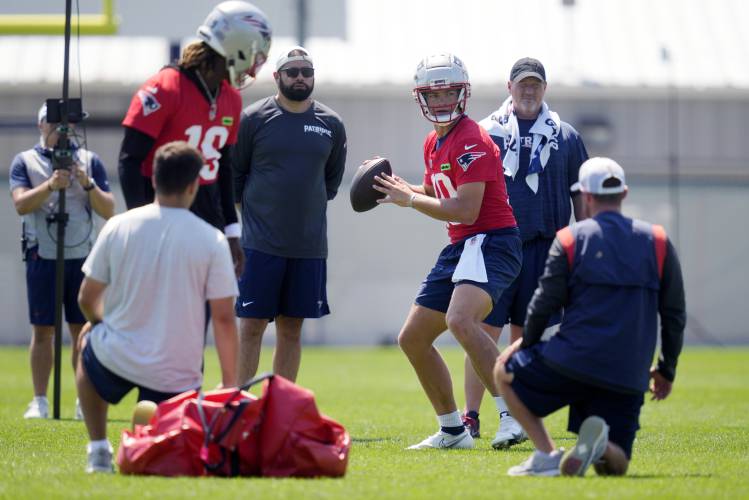 New England Patriots quarterback Drake Maye (10) sets to pass while observed by the coaching staff during an NFL football training camp, Friday, July 26, 2024, in Foxborough, Mass. (AP Photo/Charles Krupa)