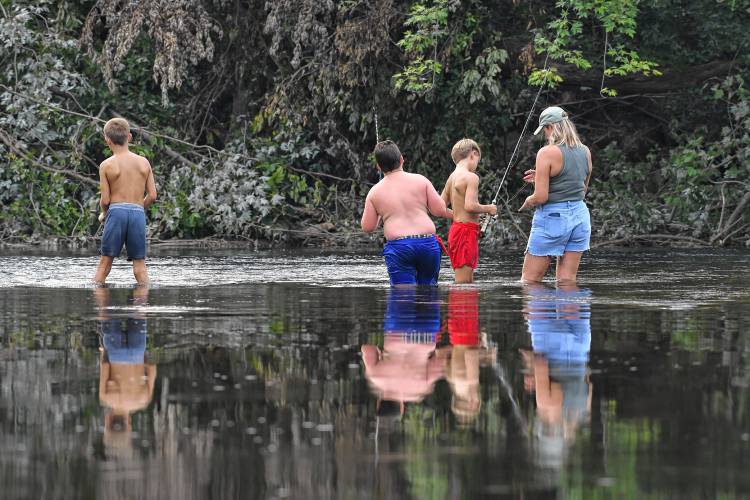 Three young fishermen and their chaperone are reflected in the Deerfield River while casting their lines in Deerfield. Three young fishermen and their chaperone are reflected in the Deerfield River while casting their lines in Deerfield.