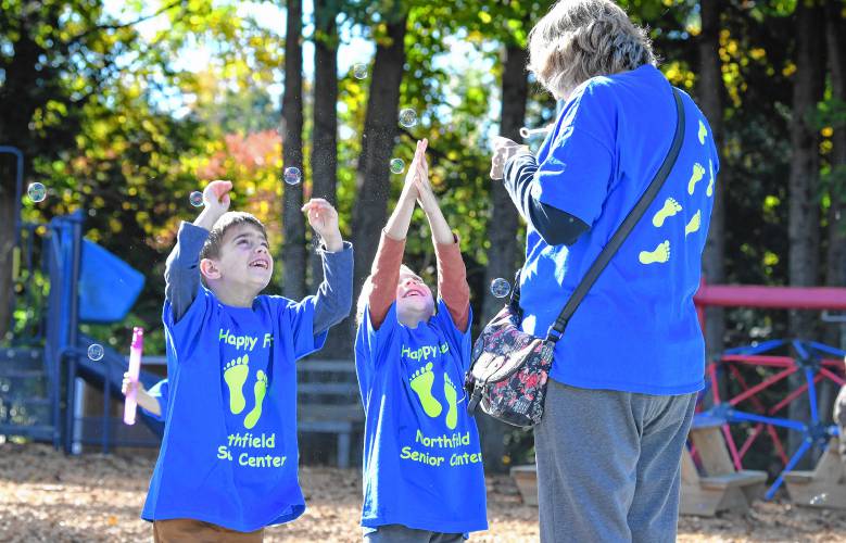 As part of the Happy Little Feet walking program, Northfield Elementary School kindergartners and members of the Northfield Senior Center blow and catch bubbles on the school playground on Tuesday.