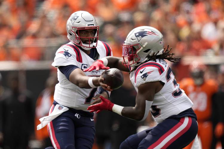 New England Patriots quarterback Jacoby Brissett (7) hands the ball off to running back Rhamondre Stevenson (38) during the first half of an NFL football game against the Cincinnati Bengals, Sunday, Sept. 8, 2024, in Cincinnati. (AP Photo/Carolyn Kaster)