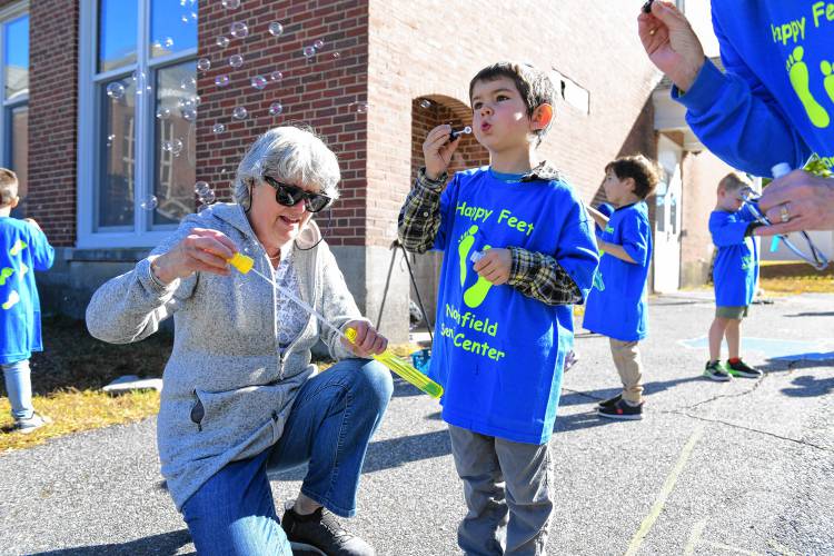 Joanne Gardner blows bubbles with her grandson Cormac McGuire on Tuesday as part of the Happy Little Feet walking program that connects Northfield Senior Center members and Northfield Elementary School kindergartners.