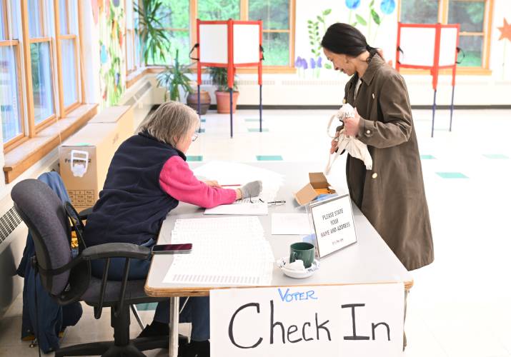 Registrar Nancy Thane checks Heath resident Thúy Lê in to vote at the Jacobs Road Municipal Center on Friday.