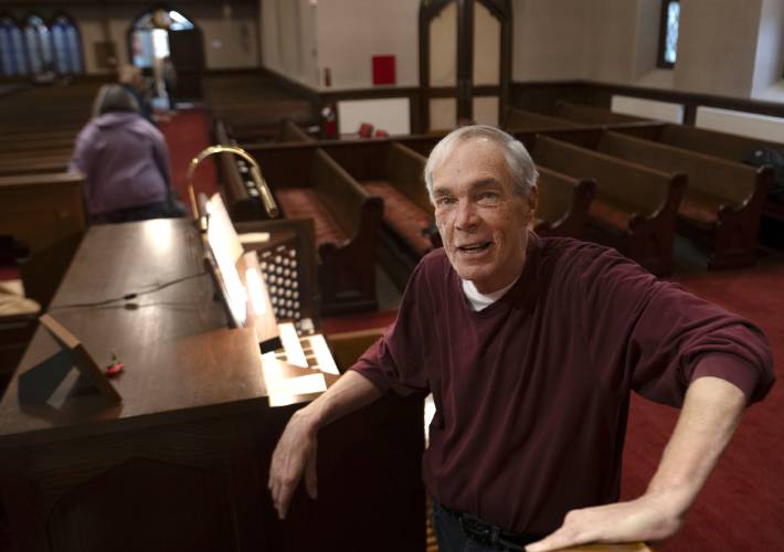 Dick Matteson stands by the organ at the First Congregational Church of Amherst where he has been the minister of music for the past 17 years. Matteson is retiring after 65 years as a church musician. 