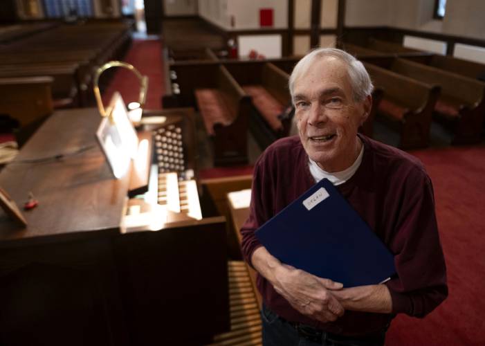 Dick Matteson stands by the organ at the First Congregational Church of Amherst where he has been the minister of music for the past 17 years. Matteson is retiring after 65 years as a church musician. 