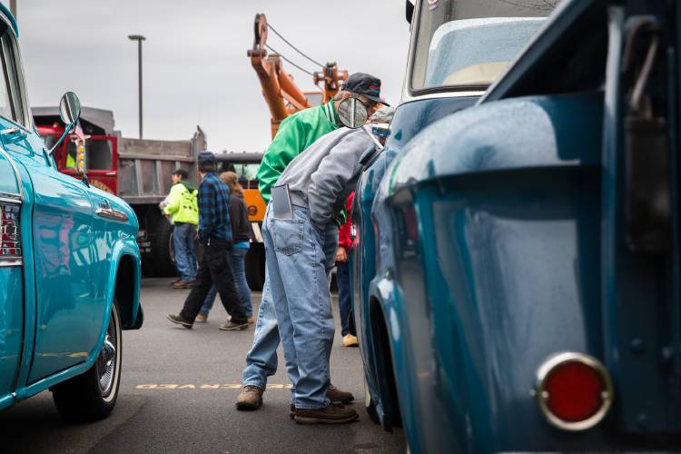 Attendees of the antique truck show at Yankee Candle Corporate Headquarters in South Deerfield look inside the engine compartment of a classic Chevy pickup truck. 
