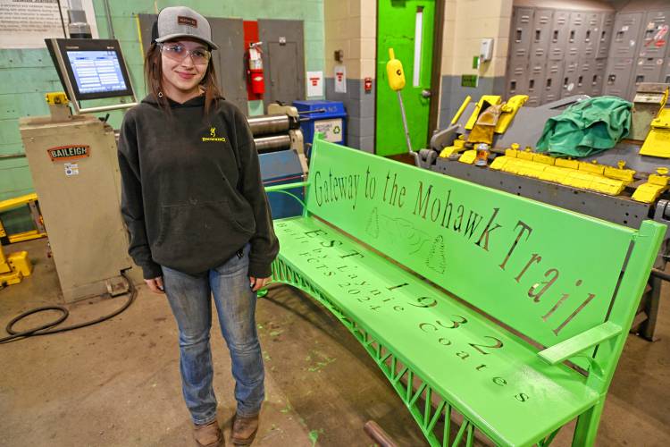 Franklin County Technical School senior Laynie Coates with her capstone project of a metal bench, with details resembling the French King Bridge, that was mounted on the Erving side of the bridge on Monday.
